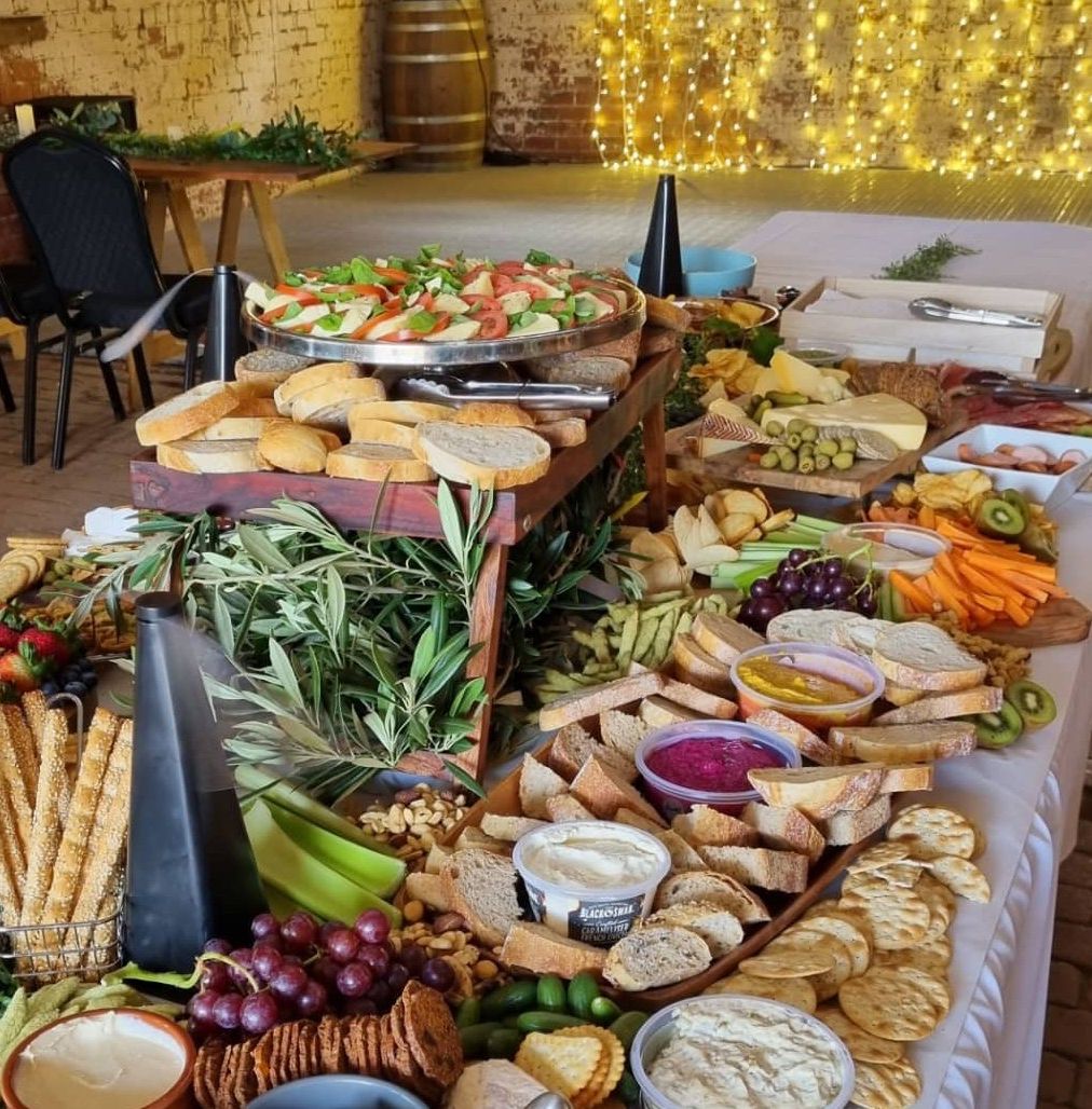 Long grazing table loaded with cheeses, cured meats, breads and fresh fruit